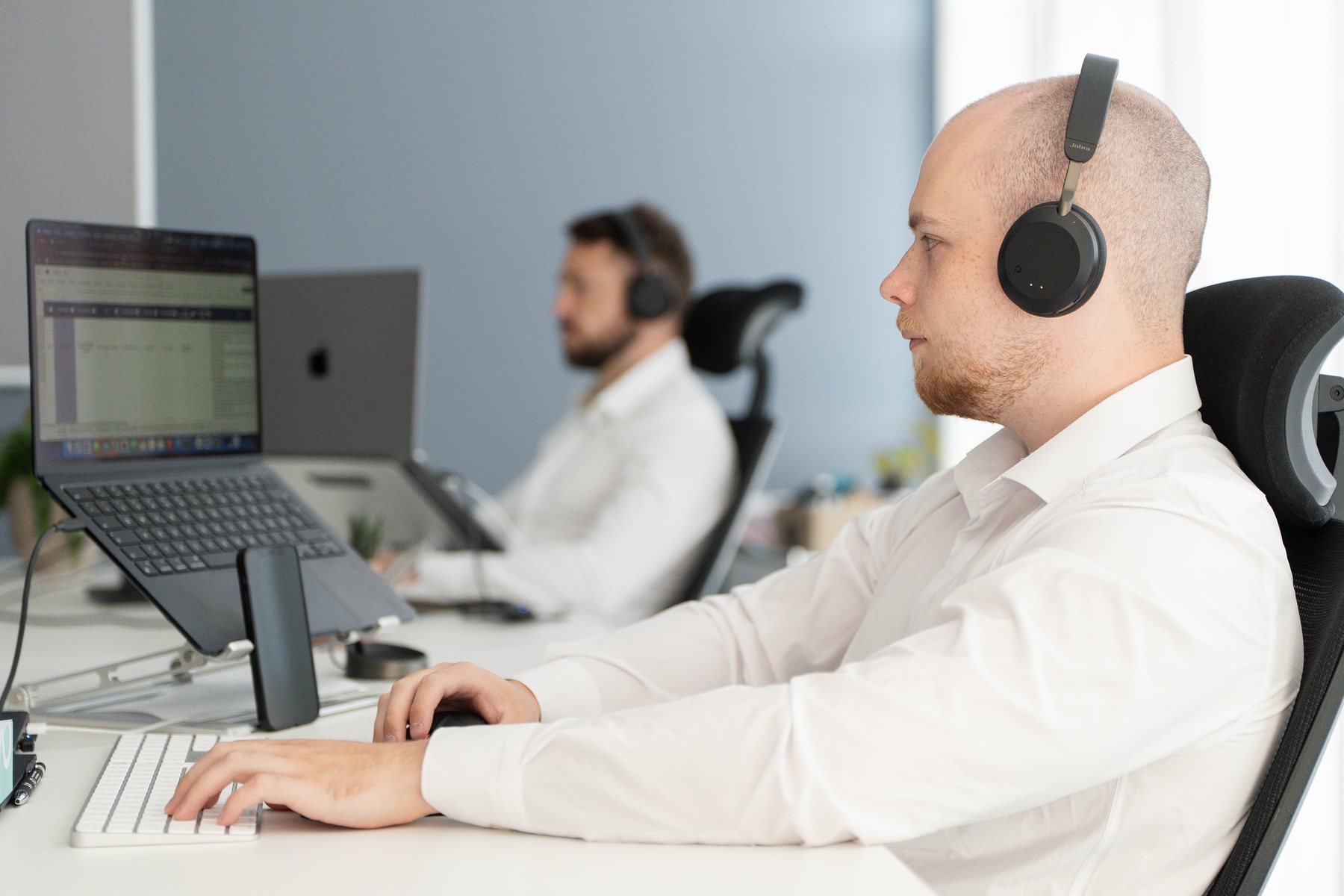 Dennis von AO Consulting telefoniert mit Headset am Schreibtisch im Büro in Bruchsal