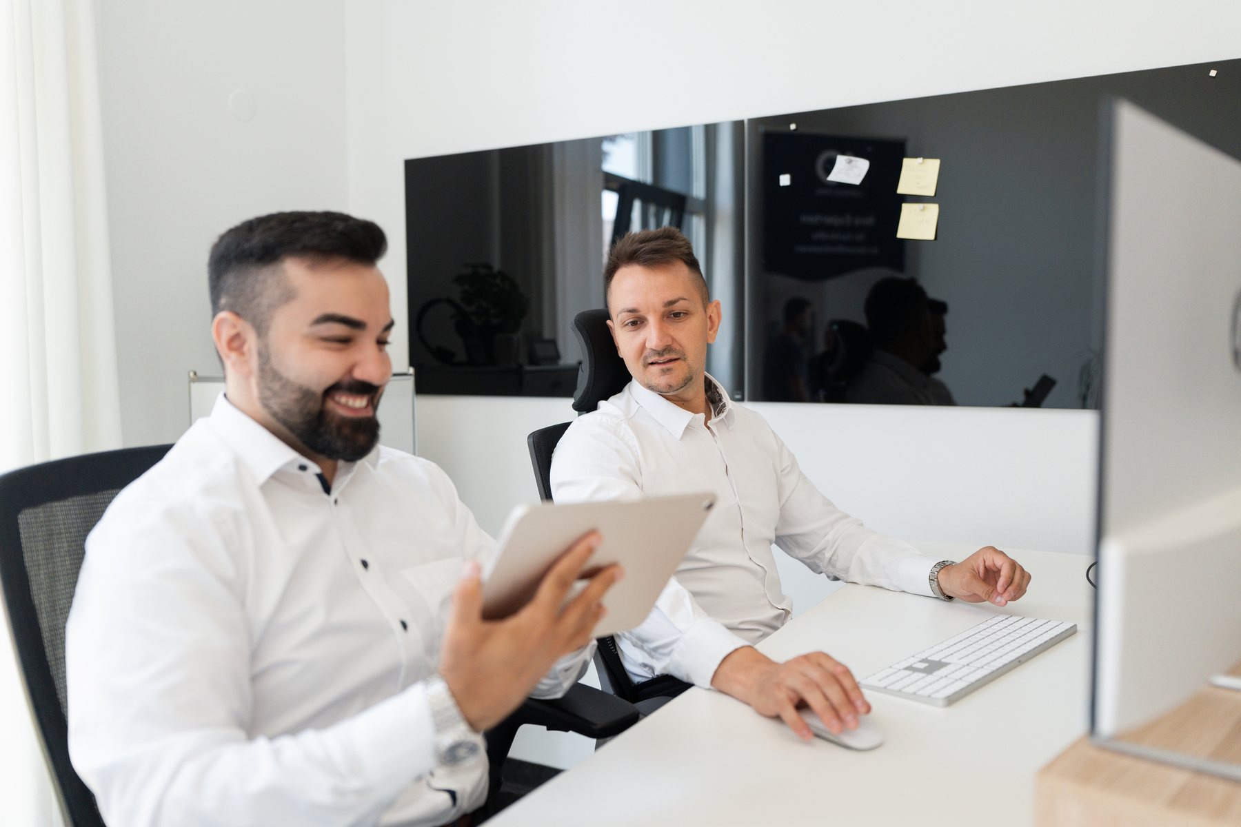 Zwei Mitarbeitende der AO Consulting stimmen einen Auftritt am Bildschirm ab