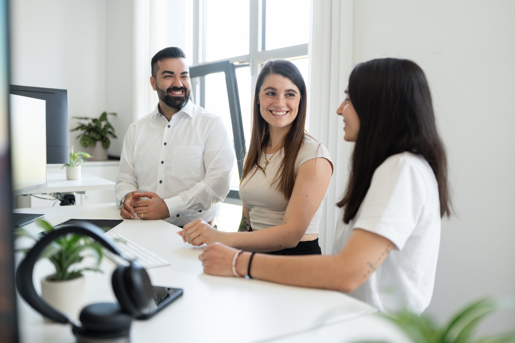 Drei Mitarbeitende der AO Consulting im Gespr&auml;ch an einem Schreibtisch in Bruchsal